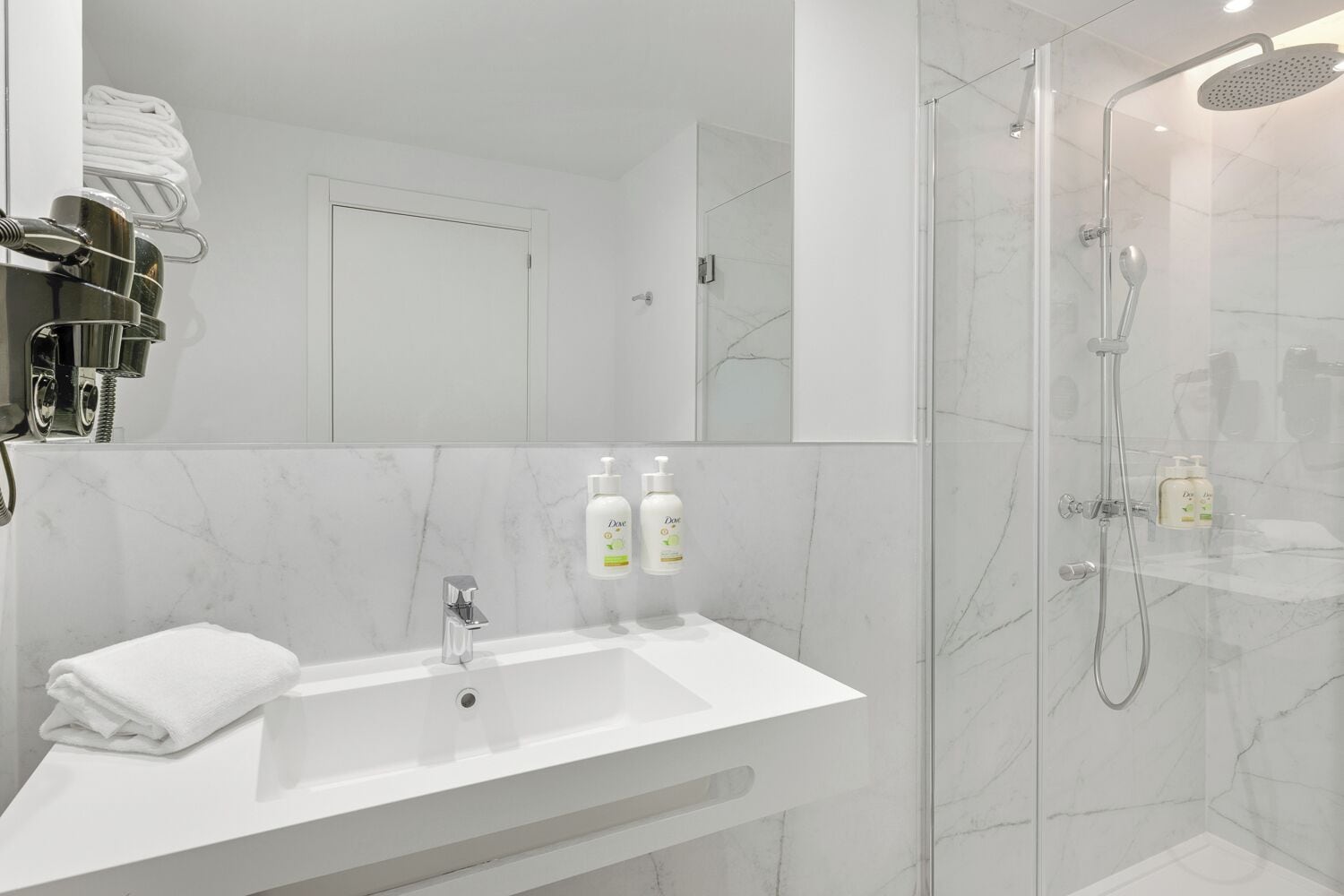 Une salle de bain moderne avec un lavabo en marbre, une cabine de douche en verre et des articles de toilette disposés sur le comptoir.