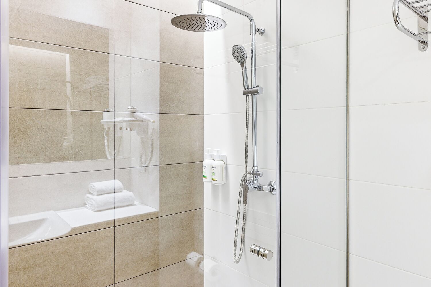 A modern shower with a handheld showerhead and a wall-mounted faucet.