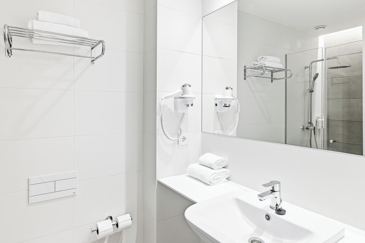 Un bany modern amb un mirall gran, un lavabo, una dutxa i penjalls per tovalloles.
