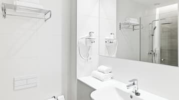 Un bany modern amb un mirall gran, un lavabo, una dutxa i penjalls per tovalloles.