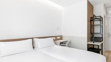 Una habitación de hotel con cama, escritorio y armario.