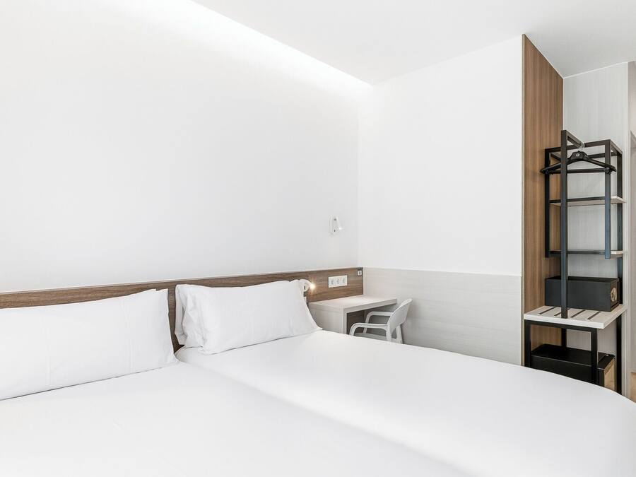 Una habitación de hotel con cama, escritorio y armario.