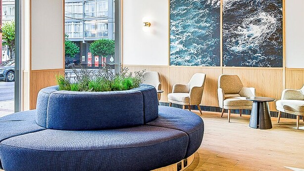 Un vestíbulo moderno con un sofá azul, una mesita y una planta en maceta.
