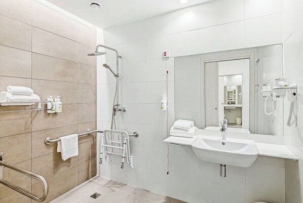 Ein modernes Badezimmer mit Dusche, Waschbecken, Spiegel und Handtuchhalter.