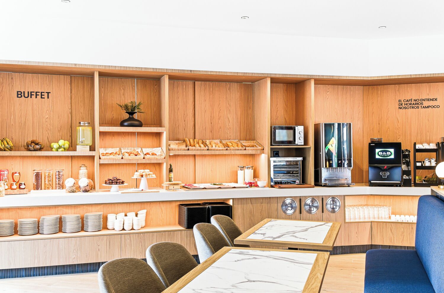 Un área de buffet con armarios de madera, una cafetera y asientos.