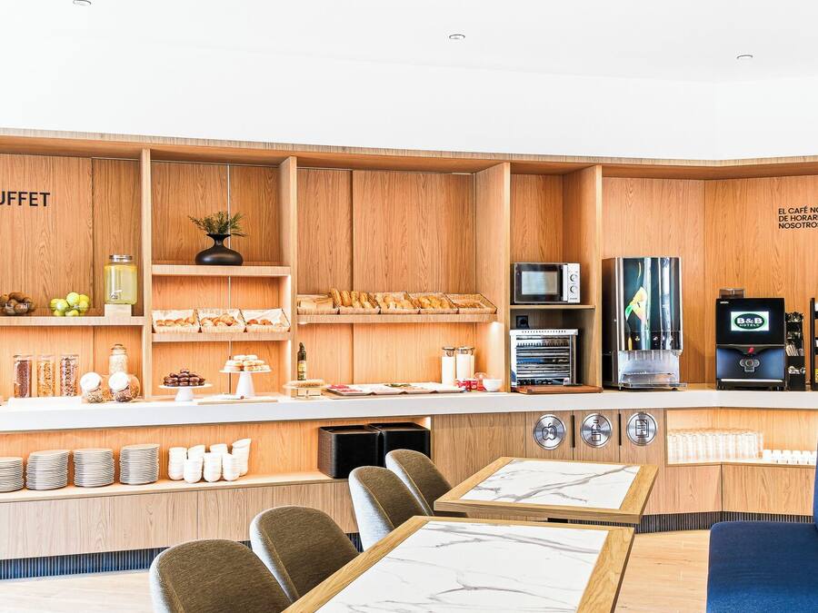 Un área de buffet con armarios de madera, una cafetera y asientos.
