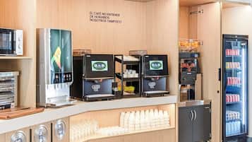 Una estación de café con varias máquinas de espresso, un refrigerador lleno de bebidas y una barra con vasos desechables.