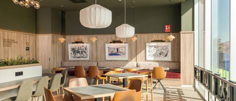 A restaurant interior with wooden panel walls, multiple seating arrangements, and pendant lighting.