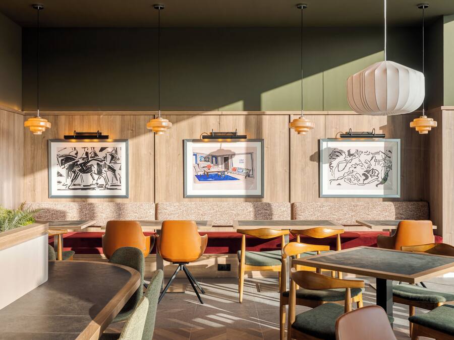 Interior de un restaurante con paneles de madera, obras de arte enmarcadas y una variedad de asientos, incluyendo cabinas y mesas.