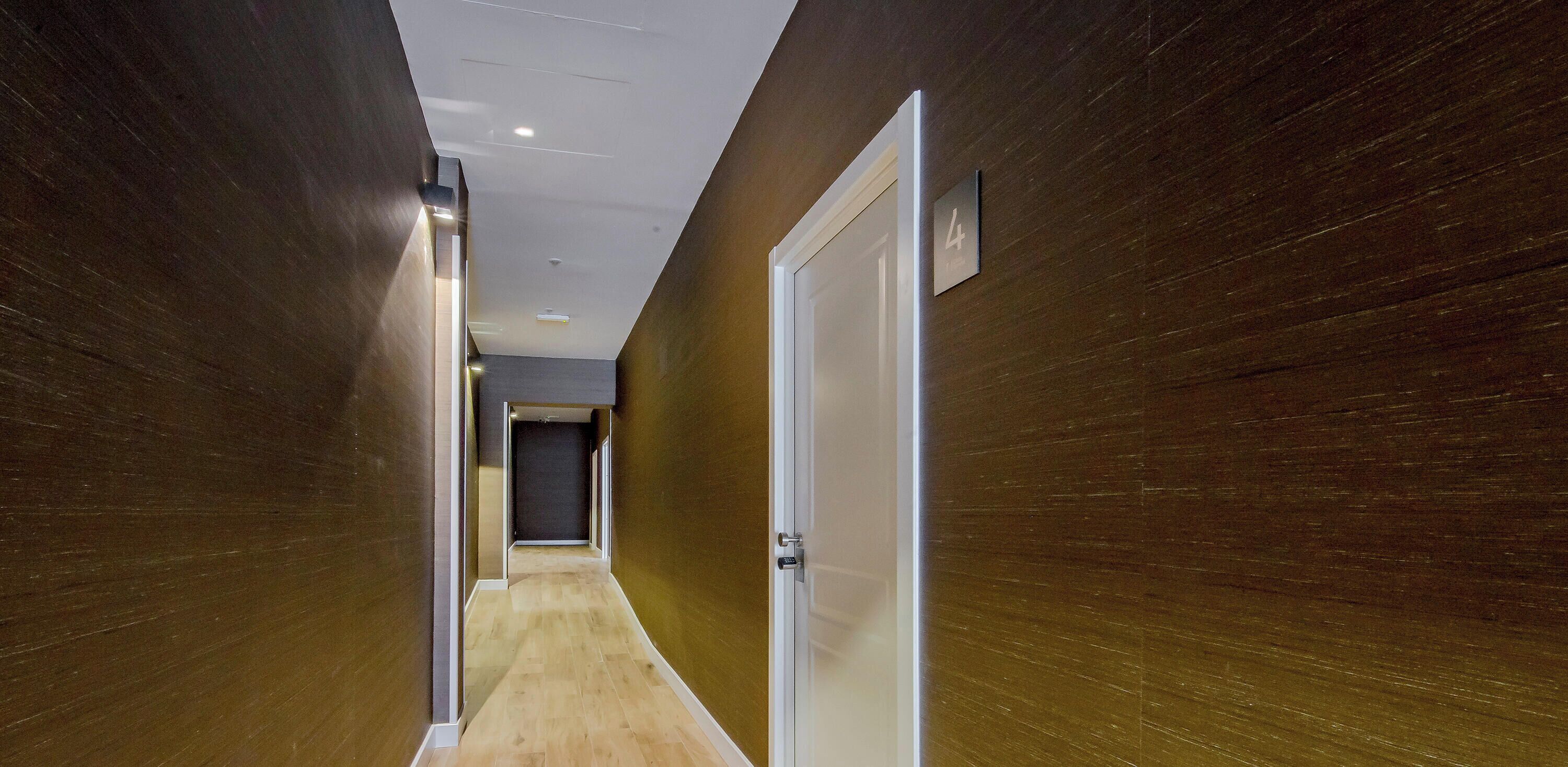 A hallway with wooden walls, a light-colored floor, and a door with a sign indicating room number 4.