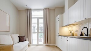 Una cocina moderna con armarios blancos, un grifo negro y una ventana con cortinas.