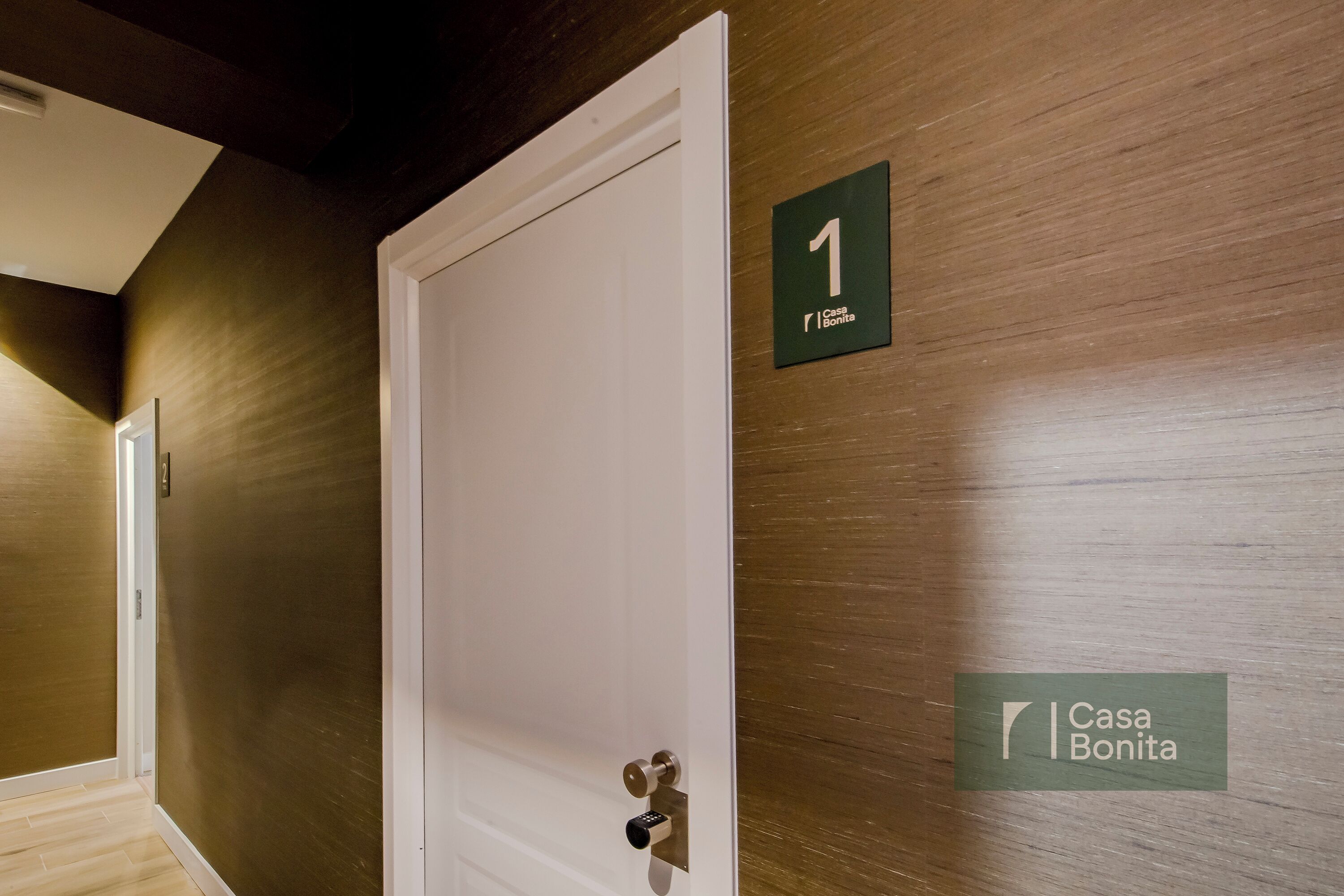 Un couloir avec une porte marquée du numéro « 1 » et une enseigne indiquant « Casa Bonita ».