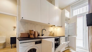 Una cocina compacta con lavadora, lavavajillas y horno empotrado.