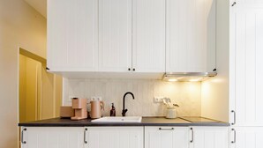 Una cocina con armarios blancos, un grifo negro y una cafetera sobre la encimera.