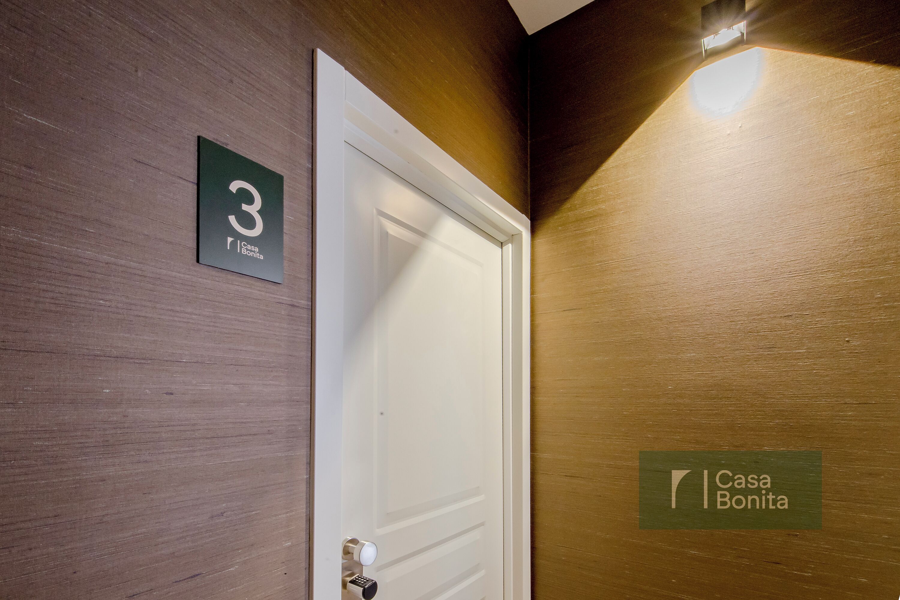 Une chambre d’hôtel avec une porte fermée, un panneau indiquant le numéro 3, et le logo de Casa Bonita.
