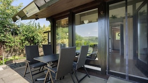 Eine Außenpatio mit Tisch und Stühlen, einer hölzernen Pergola und Blick auf die Landschaft.