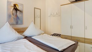 Ein Schlafzimmer mit einem Bett, einem Kleiderschrank, einem Gemälde und einem Spiegel.