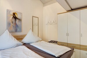 A bedroom with a bed, a wardrobe, a painting, and a mirror. - Holiday Home Hennesee with Mountain View, Private Terrace and Wi-Fi (Meschede)