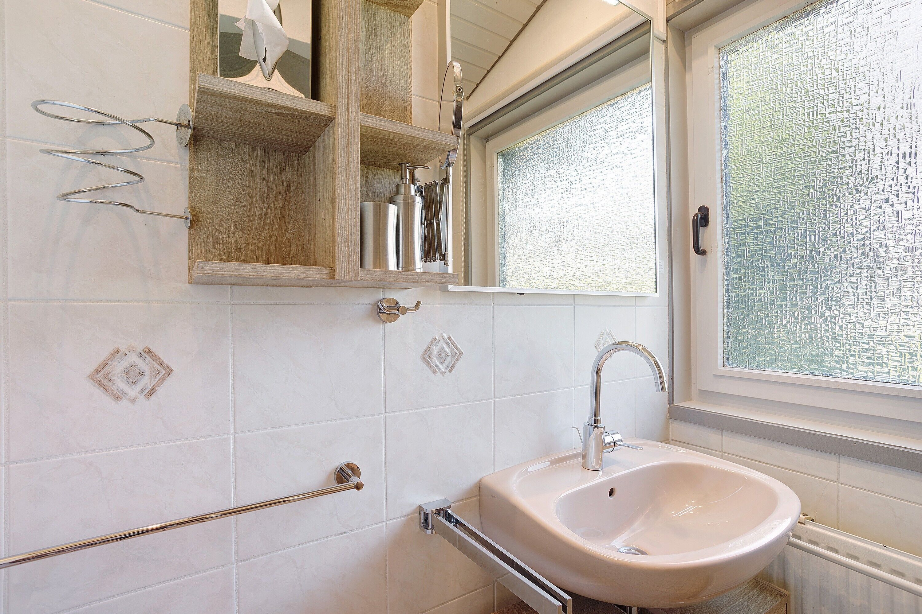 Ein Badezimmer mit Waschbecken, Spiegel und Fenster.