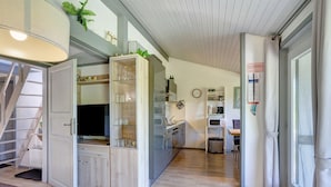 Eine moderne Küche mit integriertem Kühlschrank, einer Mikrowelle und einem Spülbecken. Es gibt einen Holzkasten mit Gläsern und eine Treppe, die zu einer anderen Ebene führt.