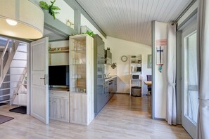 A modern kitchen with a built-in refrigerator, a microwave, and a sink. There is a wooden cabinet with glassware and a staircase leading to another level. - Holiday Home Hennesee with Mountain View, Private Terrace and Wi-Fi (Meschede)