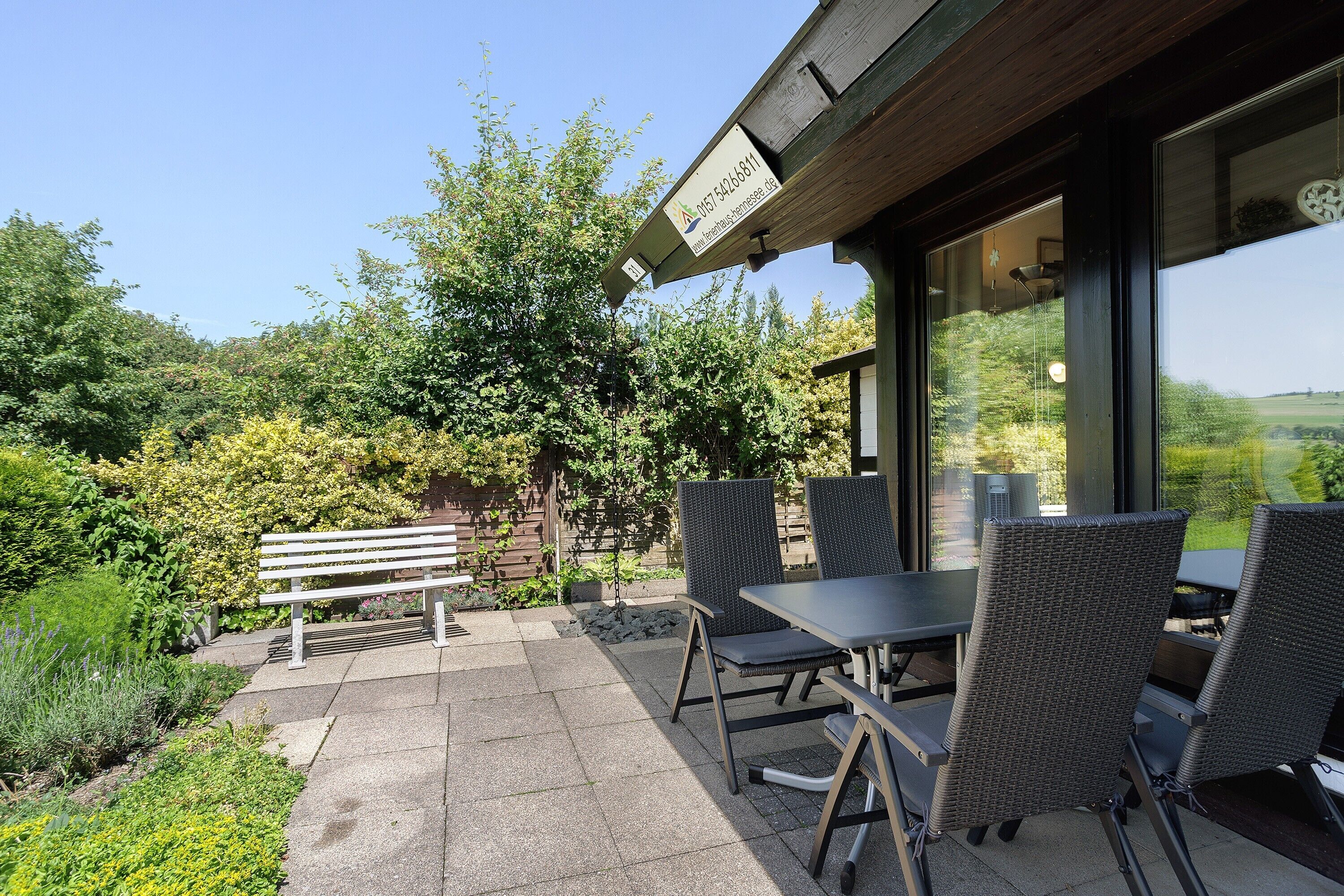 Une terrasse extérieure avec une table et des chaises, un banc et un panneau.