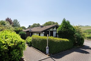 A residential house with a tiled roof, surrounded by well-maintained hedges and a paved driveway. - Holiday Home Hennesee with Mountain View, Private Terrace and Wi-Fi (Meschede)
