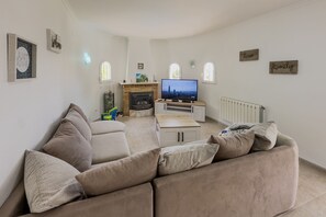 A living room with a sofa, TV, fireplace, and decorative wall signs. - Villa Blanca Del Mar - Calpe Premium Panorama (Calpe)