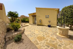 A courtyard with stone flooring, a statue, and a building with a tiled roof. - Villa Blanca Del Mar - Calpe Premium Panorama (Calpe)