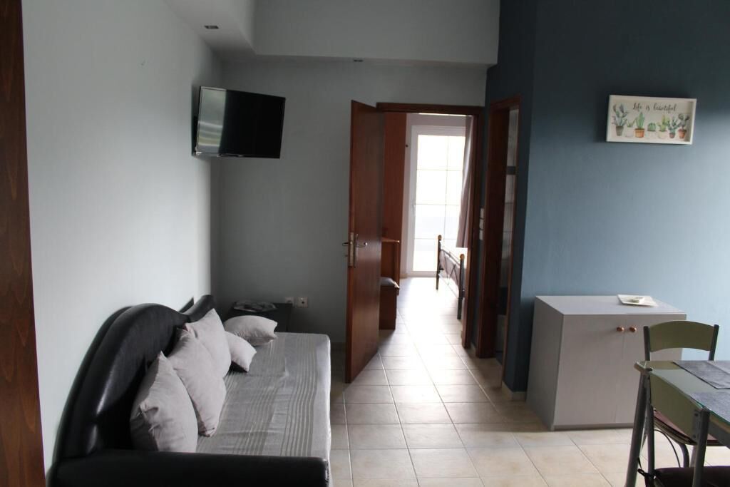 A room with a bed, a desk, a television, and a door leading to another room.