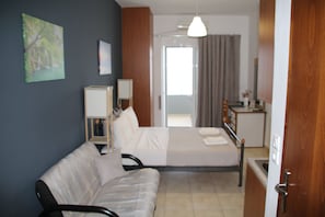 Ein Hotelzimmer mit Bett, einer Sitzecke, einem Schreibtisch und einem Fenster mit Vorhängen.