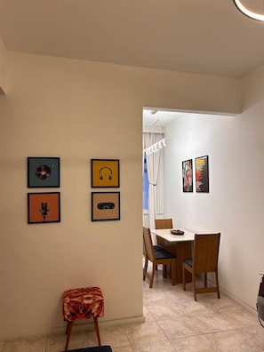 A dining area with a table and chairs, a small stool, and wall-mounted artwork. - Top apartment 350m from Copacabana beach (Rio de Janeiro)