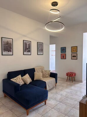 A living room with a dark blue sofa, a white door, and framed pictures on the wall. - Top apartment 350m from Copacabana beach (Rio de Janeiro)