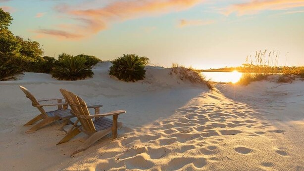 Een zandstrand met zonsondergang en een stoel.