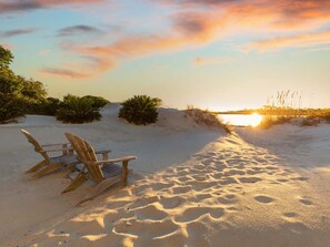 A beach scene with sand, a sunset, and a chair. - Gull Cottage | Couple's Retreat w. Deck, Steps to Beach! (Tybee Island)