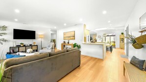 A modern living room with a sofa, a TV, and a dining area with a kitchen in the background. - 30+ Stay Perfect For Families Mins 2 San Diego Bay (San Diego)