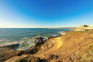 A coastal landscape with rocky terrain, a clear blue sky, and a distant pier. - 30+ Stay! Ocean Front, Perfect For Families (San Diego)