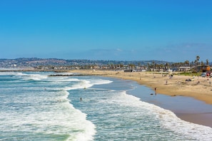 A beach with waves, people, and buildings in the background. - 30+ Stay! Steps 2 Beach & Pier -Parking Available (San Diego)
