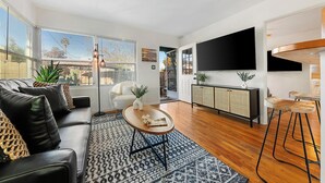 En moderne stue med sofa, sofabord og et fjernsyn monteret på væggen.