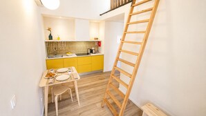 Een keuken met gele kastjes, een houten tafel en een ladder.