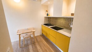 Een kleine keuken met een eettafel en stoelen, een geïntegreerde spoelbak en een spatwand.