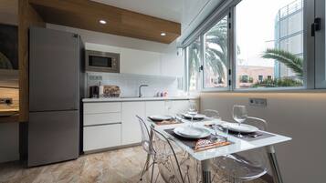 Cocina moderna con refrigerador, microondas y mesa de comedor para dos.