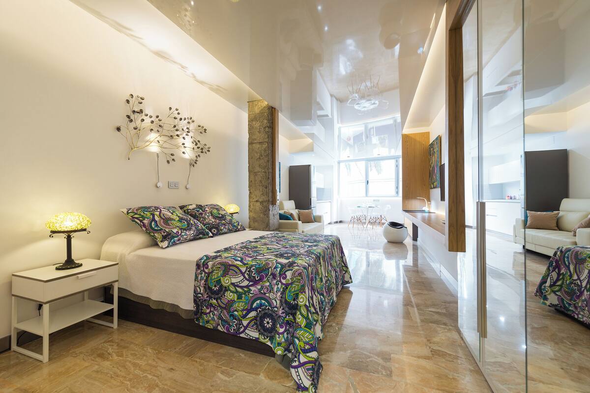 A modern bedroom with a large bed, bedside table, and a decorative wall piece.