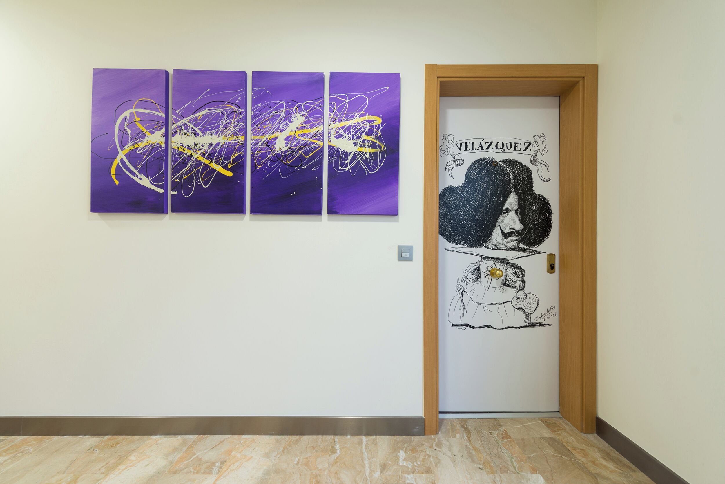 A hallway with a purple abstract painting, a door with a black and white illustration, and a marble floor.