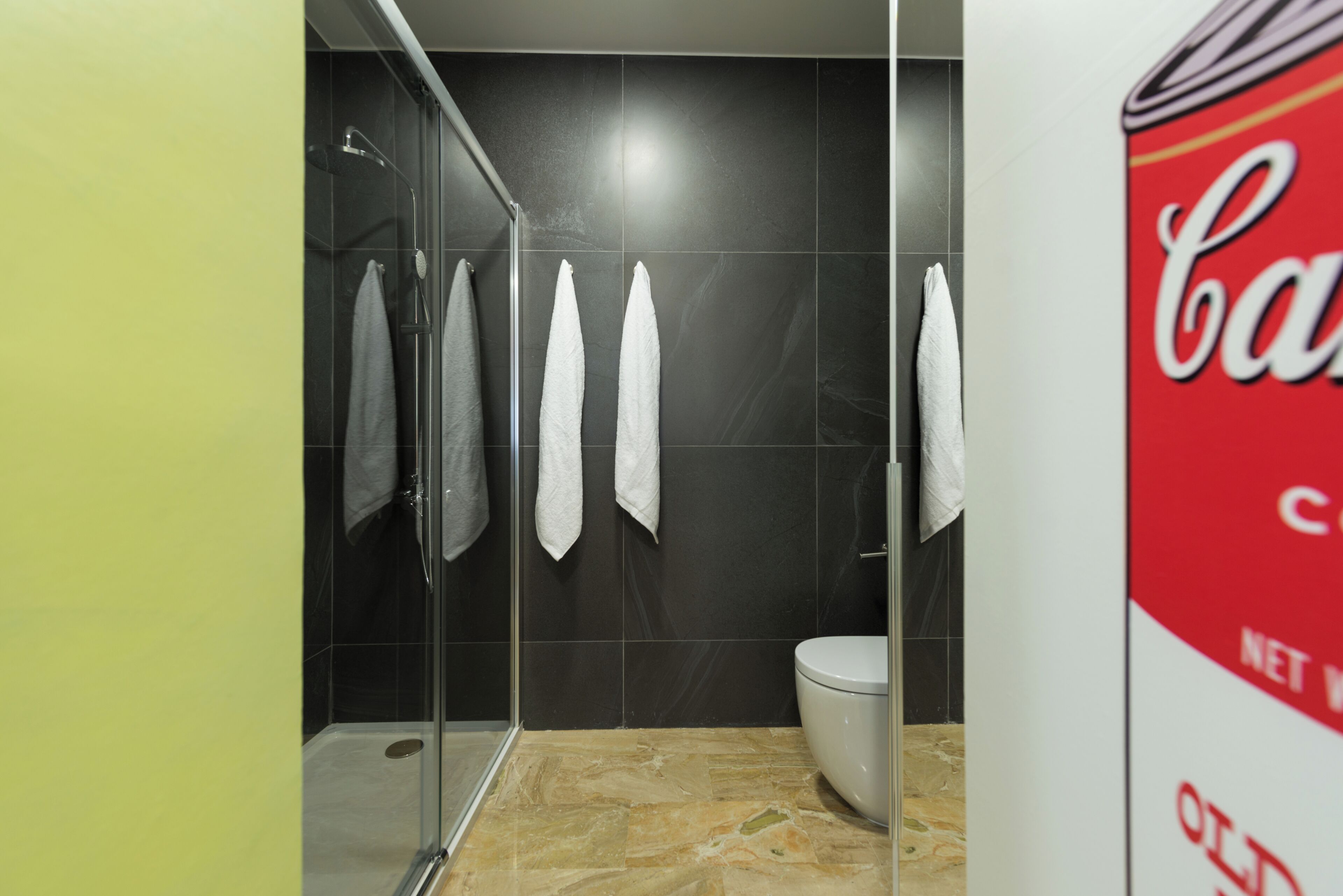 Un baño con cabina de ducha de vidrio, un inodoro y un toallero en la pared con varias toallas blancas.