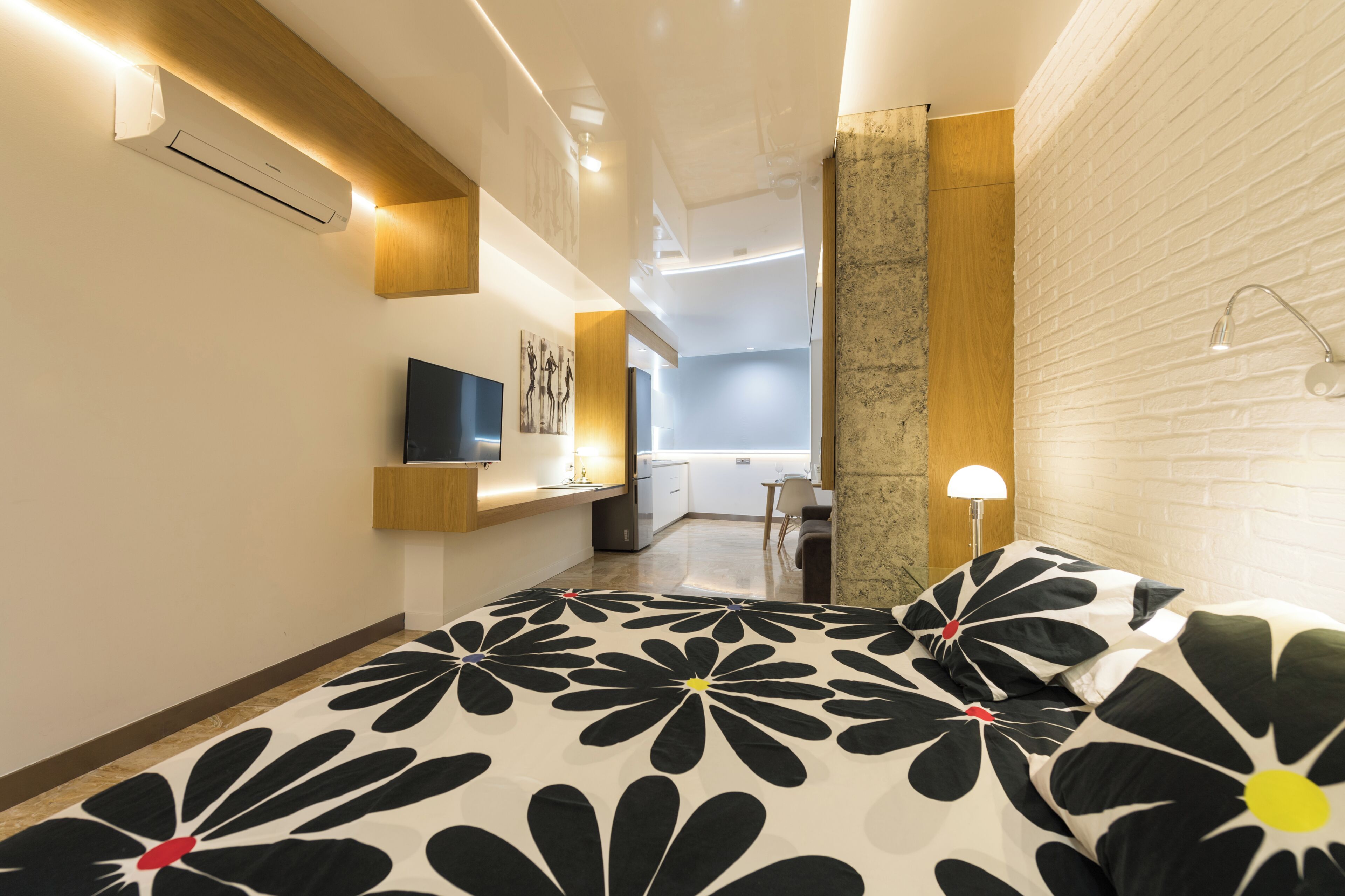 Una habitación de hotel moderna con cama, televisor, escritorio y baño.