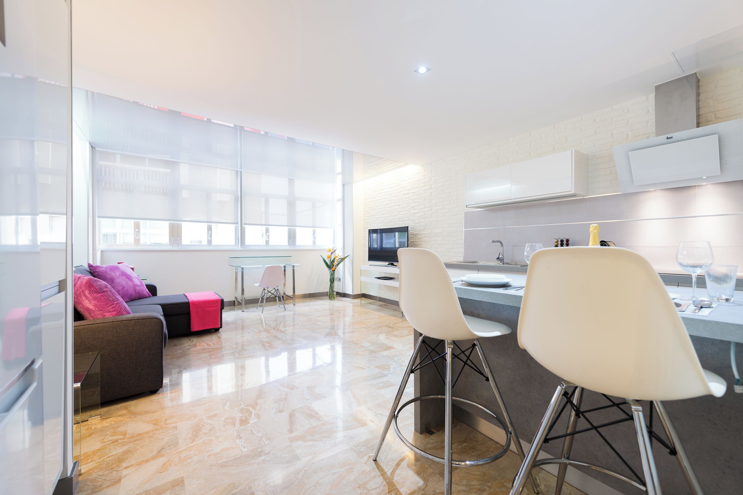 Una cocina moderna con comedor, televisor y una pared divisoria de vidrio.