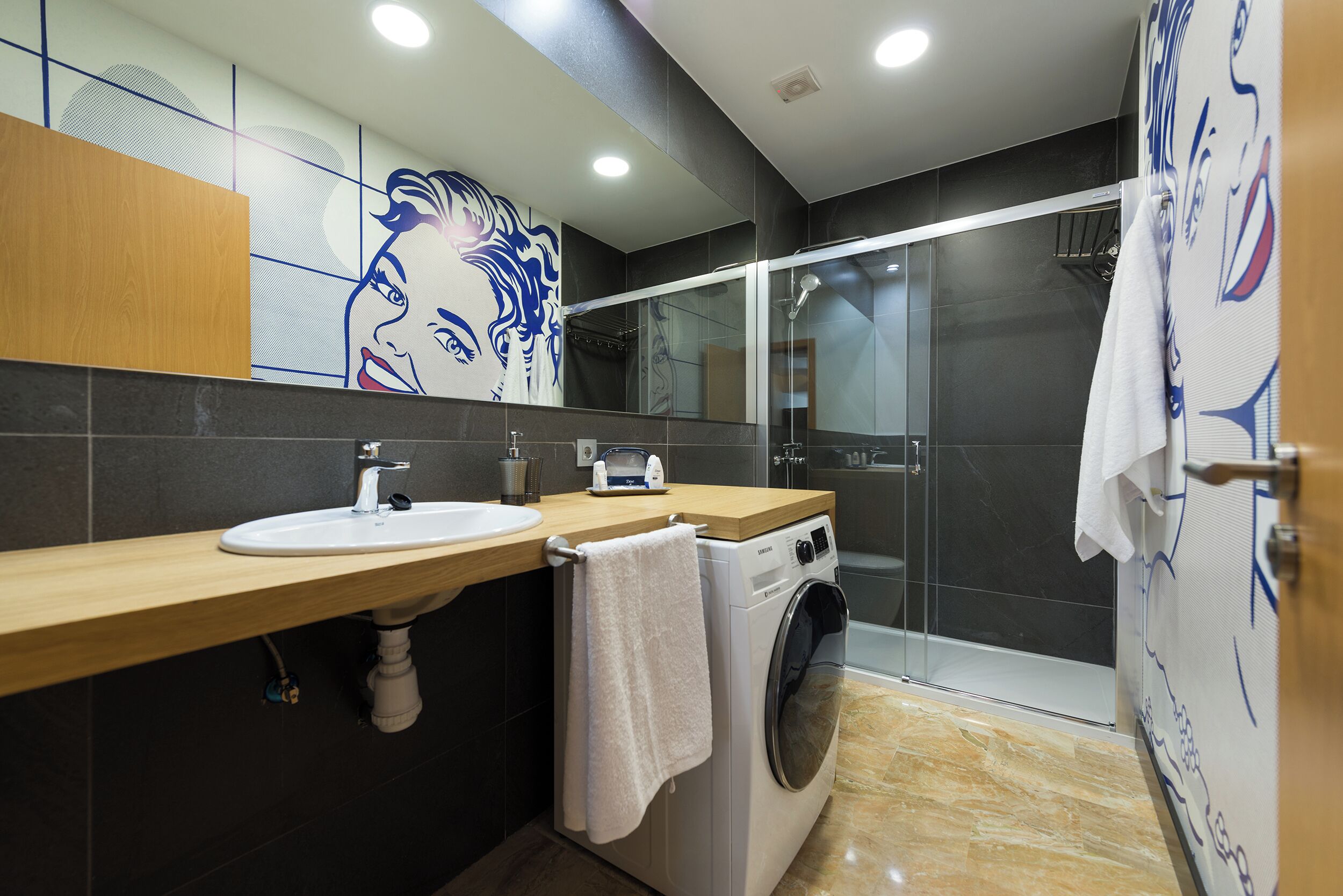 A modern bathroom with a sink, mirror, towel rack, and a glass-enclosed shower.