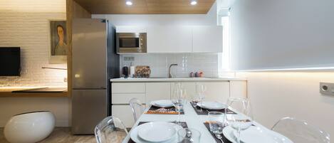 Une cuisine moderne avec des meubles blancs, un réfrigérateur en acier inoxydable et un four à micro-ondes.