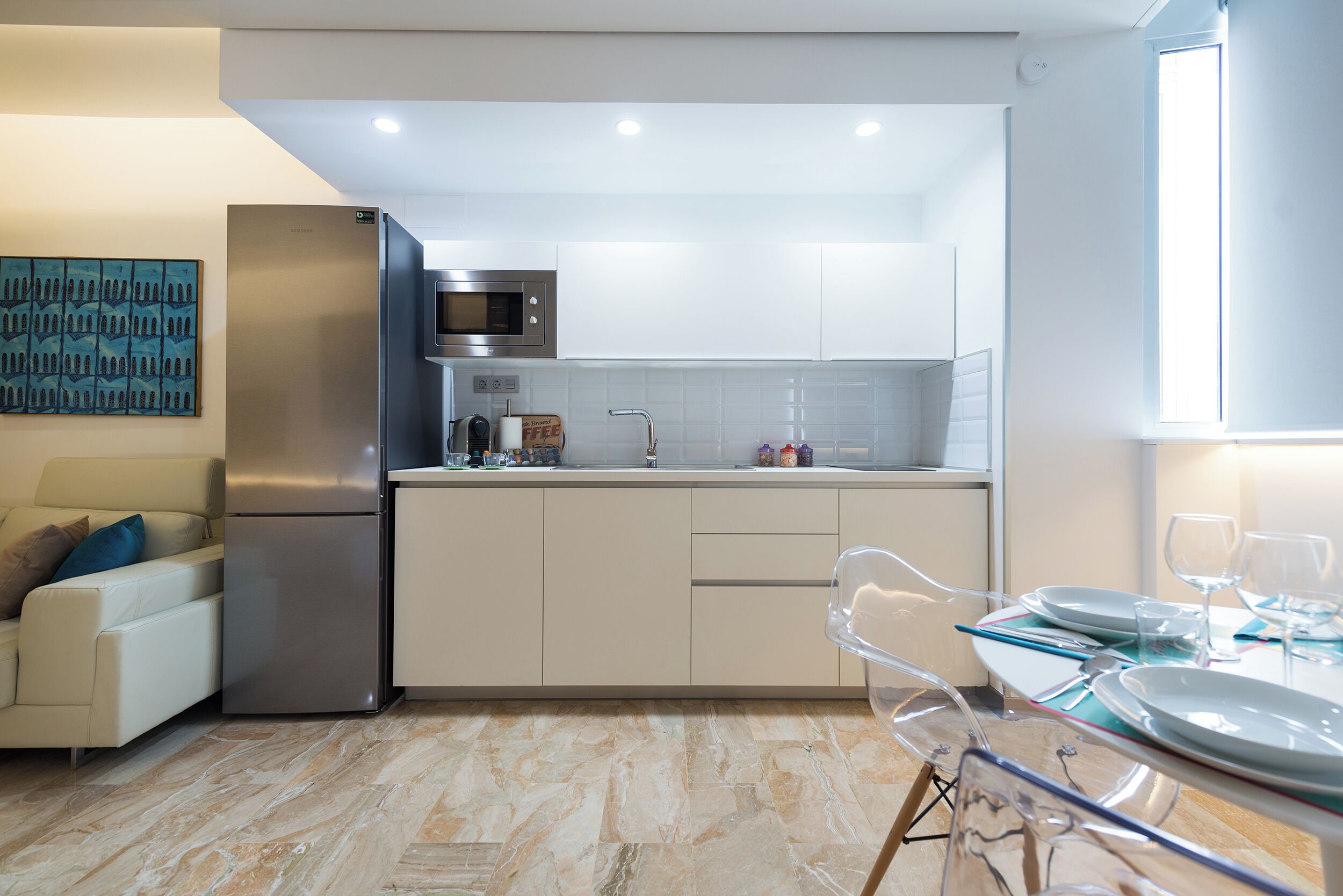 Eine moderne Küche mit Kühlschrank, Mikrowelle und weißen Schränken.